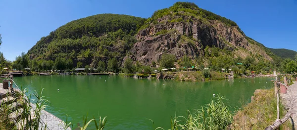 A beautiful view of the pond on a hot summer day is located at the foot of two mountains with stony slopes and overgrown with forest. — Stock Photo, Image