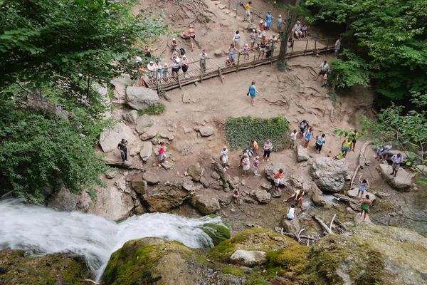 Turistas no fundo da cachoeira em pé sobre rochas da terra descansando e fotografando — Fotografia de Stock