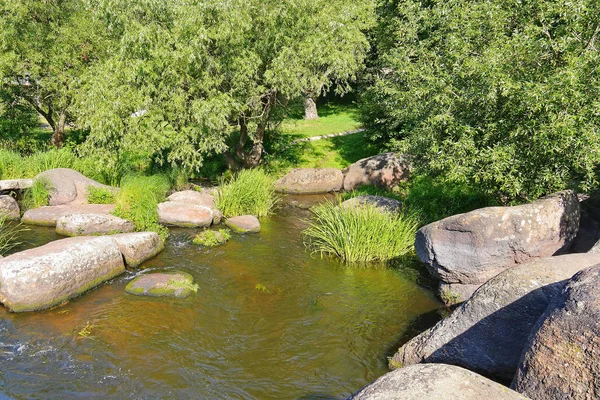 Озеро окружено огромными каменными валунами на фоне зеленой зоны парка — стоковое фото