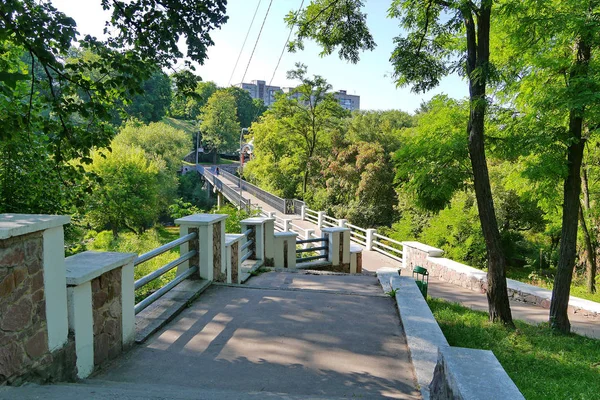 Una amplia escalera en un parque con rieles metálicos que conducen a edificios de gran altura a lo lejos — Foto de Stock