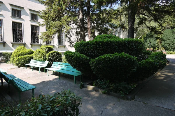 Parterres de fleurs et bancs figurés près d'un bâtiment gris de deux étages — Photo