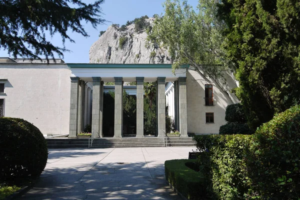 La ruelle du parc menant à l'entrée avec de grandes colonnes carrées sur le fond d'une haute montagne — Photo