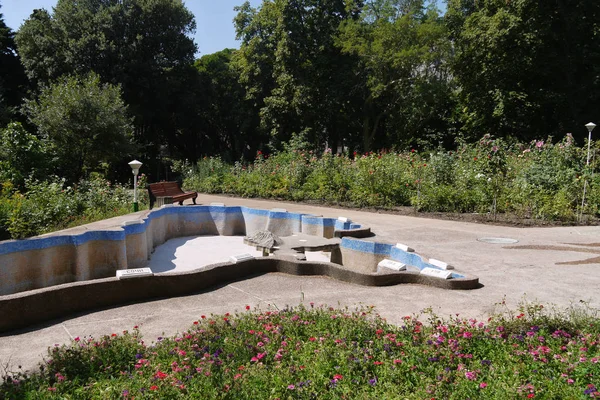 비뚤어진된 벤치와 큰 꽃 침대 공원의 중앙 빈 수영장 — 스톡 사진