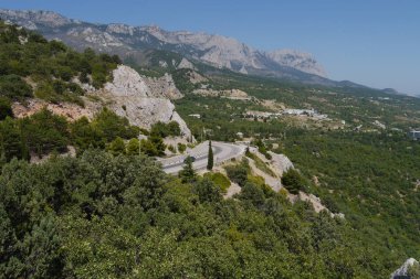 Yolun ortasında mavi gökyüzü arka plan üzerinde ağaçlarla kaplı büyük Dağları bükülmüş