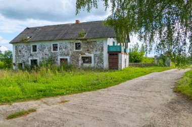 Uzun geniş bir yol terk edilmiş evleri ve uzun boylu, yemyeşil ağaçlar arka plan üzerinde çim çevrili