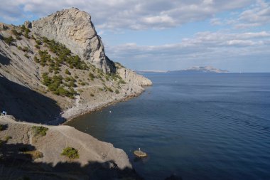 Uçsuz bucaksız, uçsuz bucaksız bir denizin arka planında çimlerle kaplı güzel kıyı yamaçları