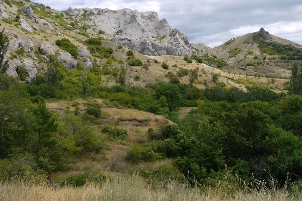 Området nedanför berget små är täckt med en sällsynt buskar och förkrympta träd. Med stora stenblock liggande på backarna — Stockfoto