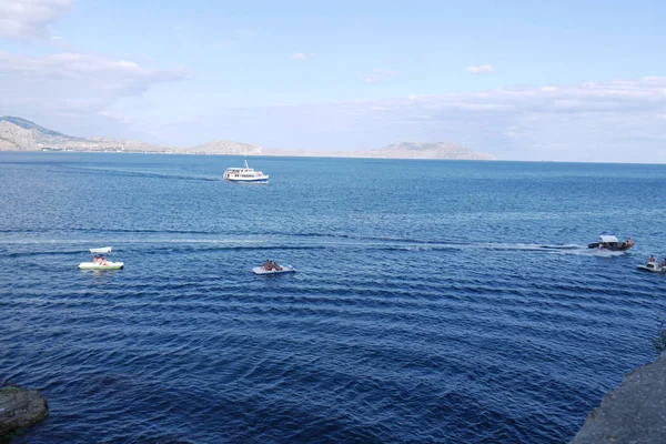 Bir büyük liner ve küçük tekne rock bay yakınındaki mavi deniz dalgaları üzerinde — Stok fotoğraf