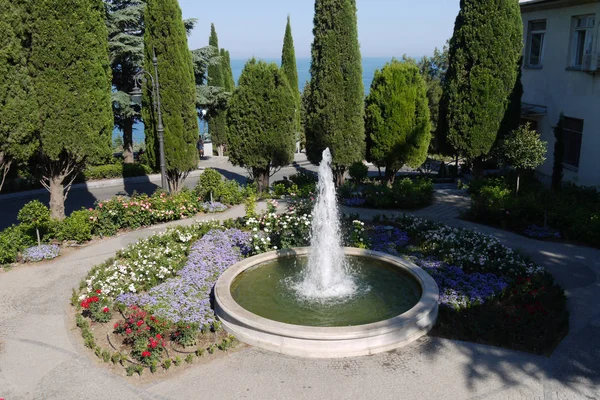 Fontaine ronde soignée parmi les parterres de fleurs avec de belles fleurs — Photo