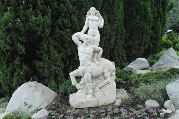 A white statue of a woman at a centaur against a background of green tuy in the park — Stock Photo, Image