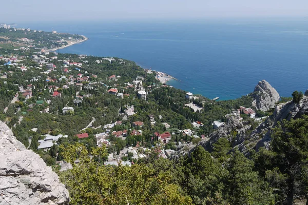 Ένα μικρό βράχο στο φόντο του μια όμορφη ήσυχη παραλιακή πόλη κάτω από ένα καταγάλανο ουρανό — Φωτογραφία Αρχείου