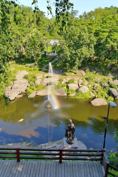 Hermosa fuente en medio de un amplio río rocoso en el fondo de árboles verdes densos —  Fotos de Stock