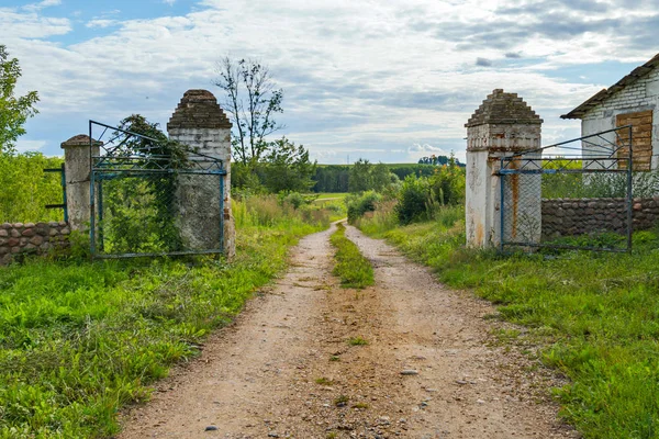 Ett gammalt staket på bakgrunden av en fältet vägen under en blå himmel — Stockfoto