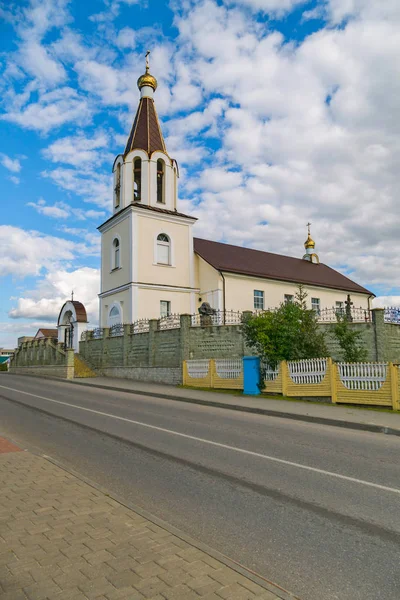 Маленька церква, оточена високим парканом на тлі хмарного блакитного неба — стокове фото