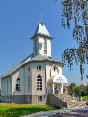 Kilise windows farklı şekil ve mavi gökyüzü bulutlar olmadan karşı kule üzerinde bir uydu çanağı ile beyaz duvarlı.