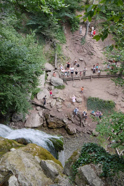 Turister titta på vattenfallet från en utsiktsplats som ligger på en nedstigning från en klippa — Stockfoto