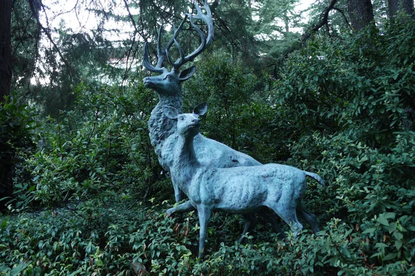 Dekoratív szobor ábrázoló két erdei állatok hátterében a zöld bokrok és fák — Stock Fotó