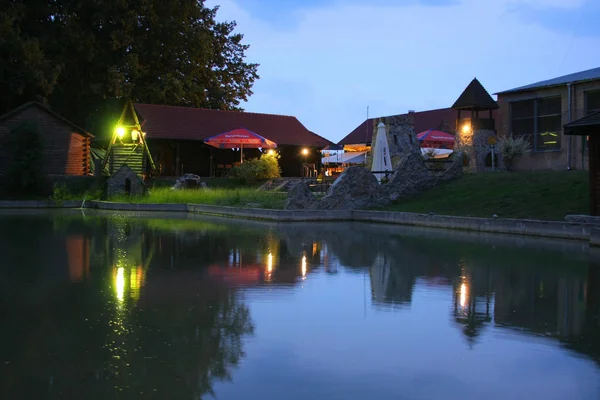 Ein kleiner See unter dem Abendhimmel vor dem Hintergrund eines gemütlichen Cafés — Stockfoto