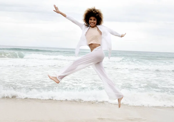 美丽的女孩与非洲头发和白色礼服跳跃在海滩上 — 图库照片