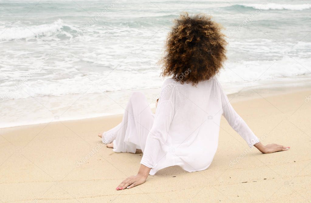 beautiful girl with afro hair and white dress relax on the beach