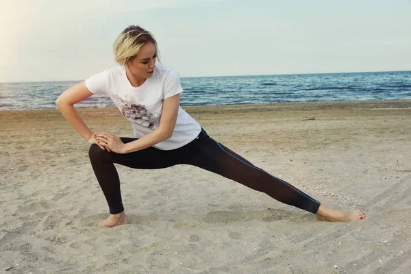 Beautiful girl doing fitness exercise on the beach — Stock Photo, Image