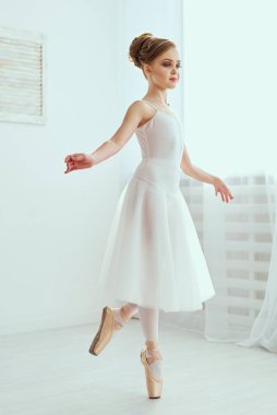 Güzel balerin poz ve ışık tam bir beyaz stüdyoda dans. Fotoğraf, büyük ölçüde bir klasik bale sanatının eşsiz güzelliğini yansıtan.