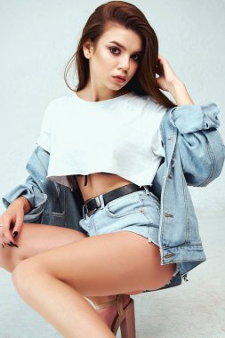 Beyaz bir arka plan üzerinde stüdyoda poz beyaz bir T-shirt ve jeans giysiler içinde güzel bir model. Yaşam tarzı, moda, güzellik