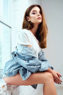 Beyaz bir arka plan üzerinde stüdyoda poz beyaz bir T-shirt ve jeans giysiler içinde güzel bir model. Yaşam tarzı, moda, güzellik