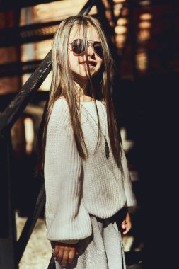 Küçük kız model Modern giyimleri, şehirde yürüyüş poz,