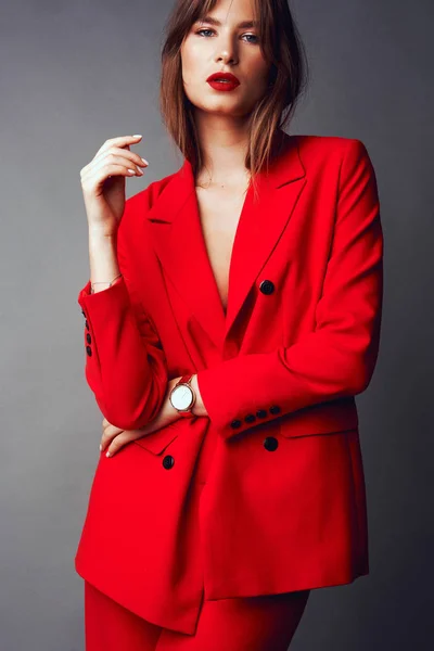 Ung kvinna i röd kostym. Grå bakgrund — Stockfoto