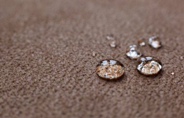 Drops of water on a water resistant fabric of brown color clipart