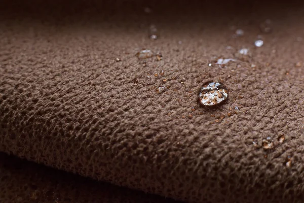 Drops of water on a water resistant fabric of brown color