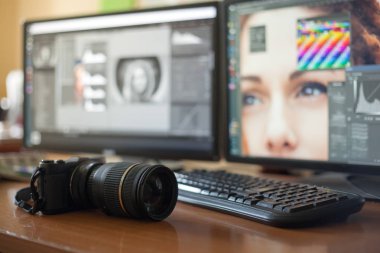 Masaüstü iki monitör, klavye, kamera, bir günlük, bir tasarımcı, bir retoucher, bir fotoğrafçı için bir palet ile. Model rötuş için özel programlarda monitörlerde görüntü ile.