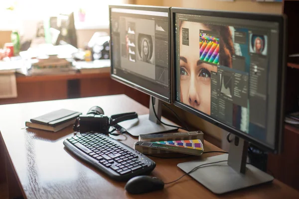 Desktop with two monitors, a keyboard, a camera, a diary, a palette for a designer, a retoucher, a photographer. With the image of the model on the monitors in special programs for retouching.