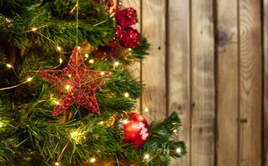 Noel oyuncak kırmızı yıldız çelenk yanındaki ahşap arka plan üzerinde kırmızı topları ile Noel ağacı üzerinde