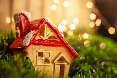 Noel oyuncak bir rakam bir lodge karda kırmızı çatılı bir çelenk arka planı yeşil tinsel mevcuttur