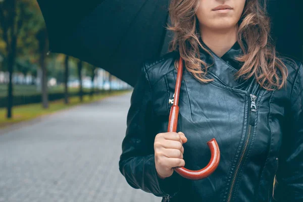 girl in a black leather jacket with a black umbrella in her hands on the mall