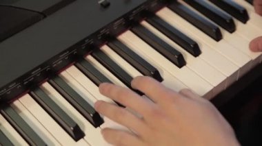 Mens eller üzerinde siyah bir synthesizer oynarken