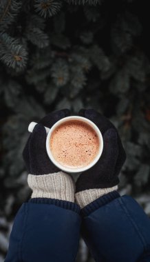 Beyaz fincan kahve arka sokakta Noel ağacının eldiven giymiş elinde