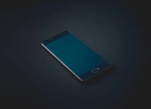 Dark-colored smartphone with the screen off lies on a black background