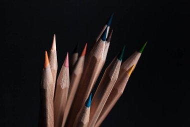 Siyah arka plan üzerine izole açık ahşaptan yapılmış farklı renklerde bilenmiş kalemler.