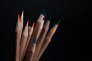 Siyah arka plan üzerine izole açık ahşaptan yapılmış farklı renklerde bilenmiş kalemler.