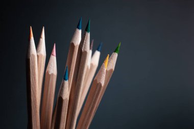 Siyah arka plan üzerine izole açık ahşaptan yapılmış farklı renklerde bilenmiş kalemler.