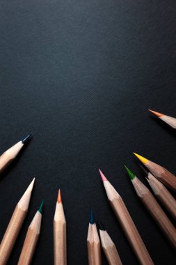 Siyah arka plan üzerine izole açık ahşaptan yapılmış farklı renklerde bilenmiş kalemler.