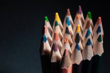 Siyah arka plan üzerine izole açık ahşaptan yapılmış farklı renklerde bilenmiş kalemler.