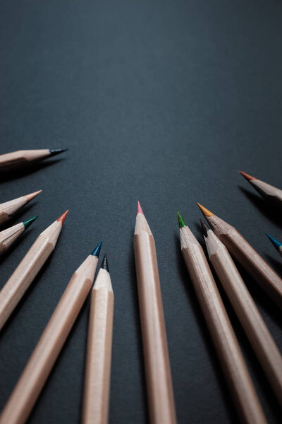 Sharpened pencils of different colors made of light wood isolated on black background.