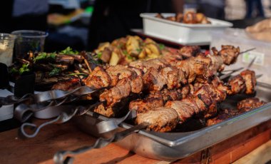 Bir eğrilik üzerinde kavrulmuş et açık havada kızarmış patates ve sebze yanında masada