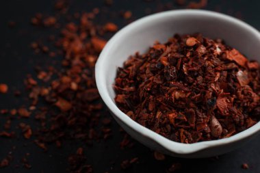 Siyah arka planda izole edilmiş beyaz bir seramik kasede kırmızı biber.