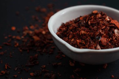 Siyah arka planda izole edilmiş beyaz bir seramik kasede kırmızı biber.