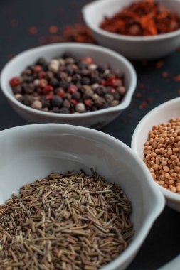 Paprika, hardal, kestane tohumu ve siyah arka planda izole edilmiş havan topunun yanında beyaz seramik kaselerde biber karışımı.